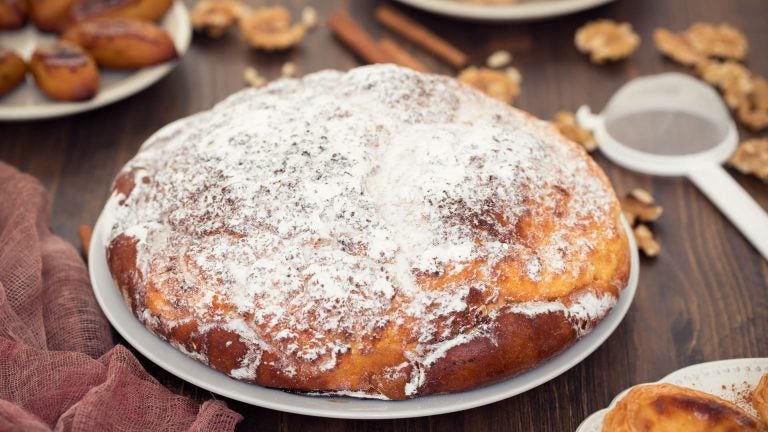 Round Portuguese sweet buns with a golden, crumbly coconut topping arranged on a table
