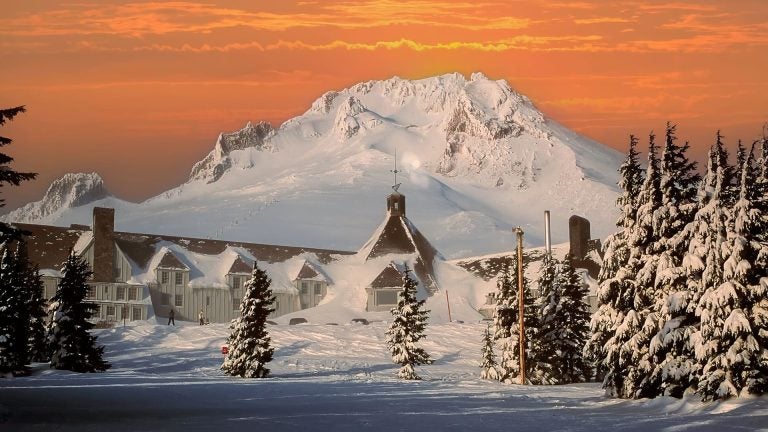 Timberline Lodge’s stone and timber exterior glowing in early morning light at the base of snow-capped Mount Hood, Oregon