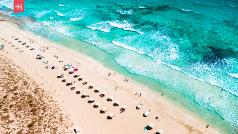 Odgórny widok na wodę i plażę z parasolkami.