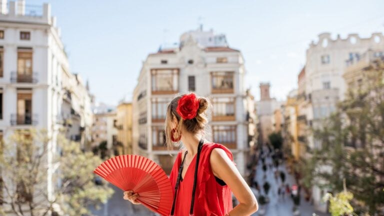 Kobieta z czerwonym wachlarzem na ulicy w Hiszpanii, nawiązująca do tradycji flamenco.