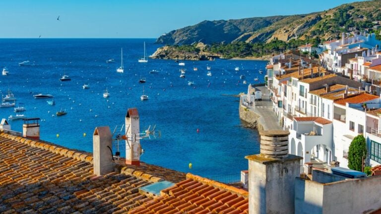 Widok na białe domy i łodzie w zatoce Cadaqués na wybrzeżu Costa Brava w Hiszpanii.