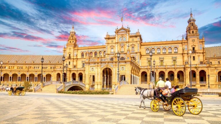 Plac Hiszpański w Sewilli z powozem konnym przed zabytkowym budynkiem.