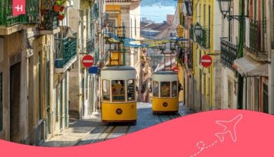 Żółte tramwaje jadą stromą ulicą w Lizbonie, otoczoną kolorowymi kamienicami.