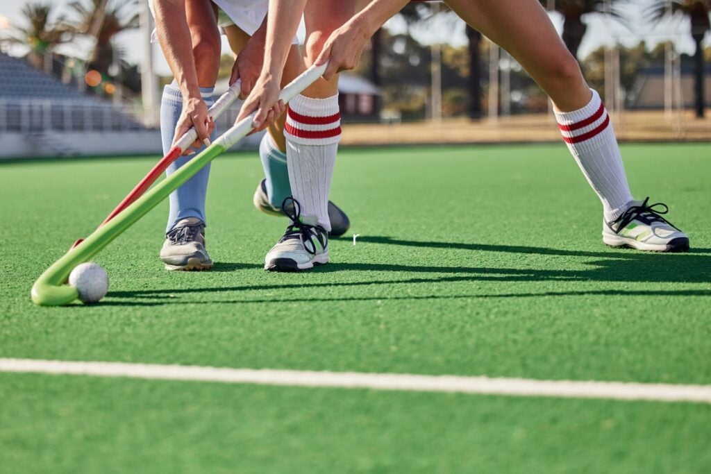Athletes are playing hockey at an outdoor stadium.