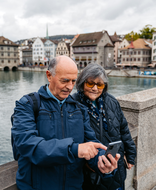 Ein älteres Paar überprüft in einer Stadt in der Schweiz Informationen auf seinem Mobiltelefon.