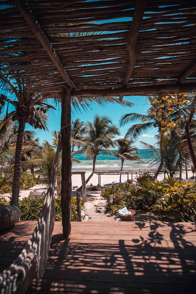 Eine Holzterrasse an einem von Palmen umgebenen weißen Sandstrand in Tulum, Mexiko