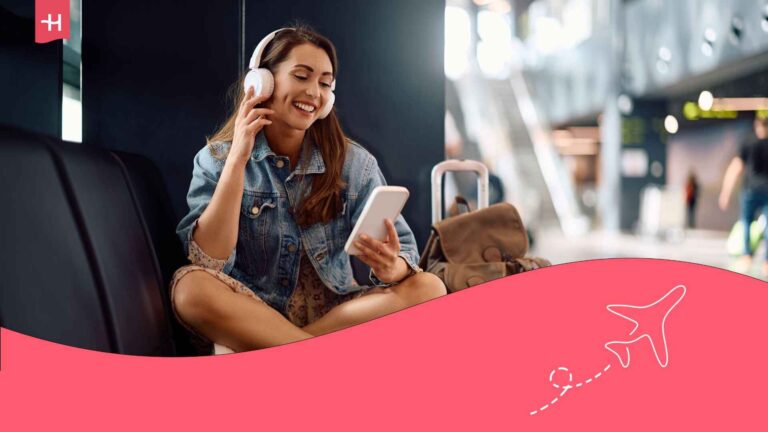 Eine lächelnde junge Frau, die im Abflugterminal mit Kopfhörern Musik hört