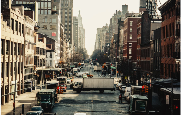 Eine belebte Straßenszene in Chelsea, mit Lastwagen, Fahrzeugen und Gebäuden, die die Allee säumen.