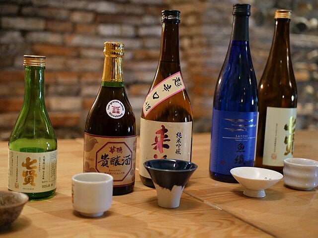 Sake-Flaschen und Gläser auf einem Tisch.
