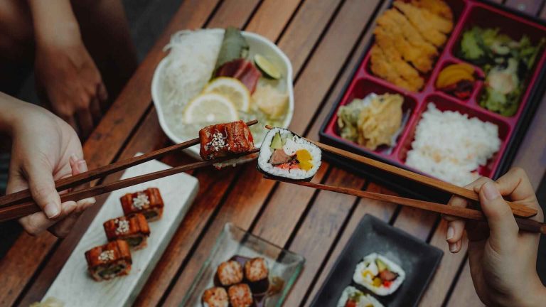 Ein Bild von Händen, die Sushi mit Stäbchen halten