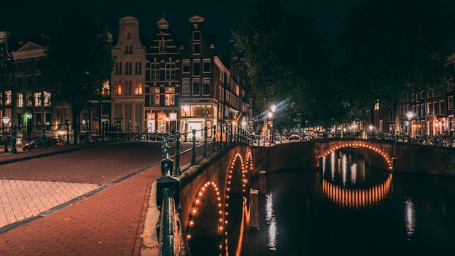 
Schwarz und rot beleuchtete traditionelle Gebäude über der Gracht, Amsterdam, Niederlande
