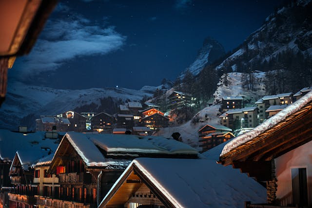 

Dorf mit Wohnhäusern auf verschneiten Hügeln in Zermatt, Schweiz
