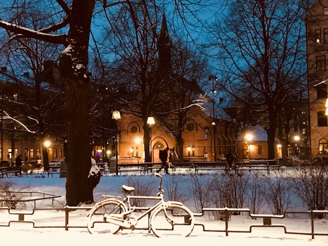 
Schneebedecktes Fahrrad in der Nähe des Zauns bei Nacht in Stockholm, Schweden