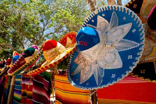 colorful Mexican sombreros and ponchos lined up outdoors
