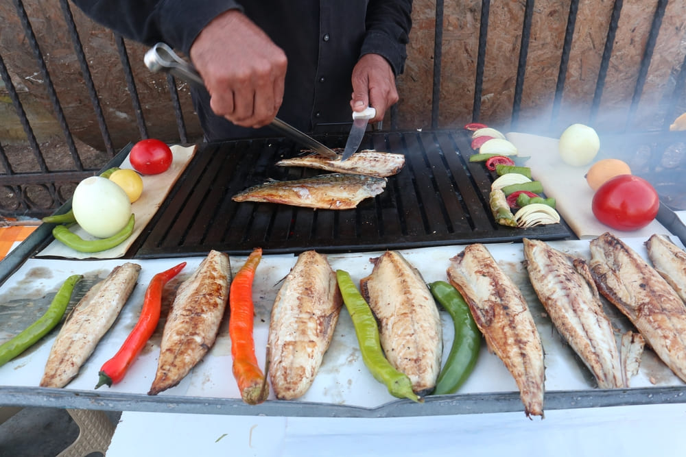 Ein türkischer Straßenkoch bereitet Balık Ekmek zu, ein beliebtes türkisches Fischgericht, das Touristen in Istanbul lieben