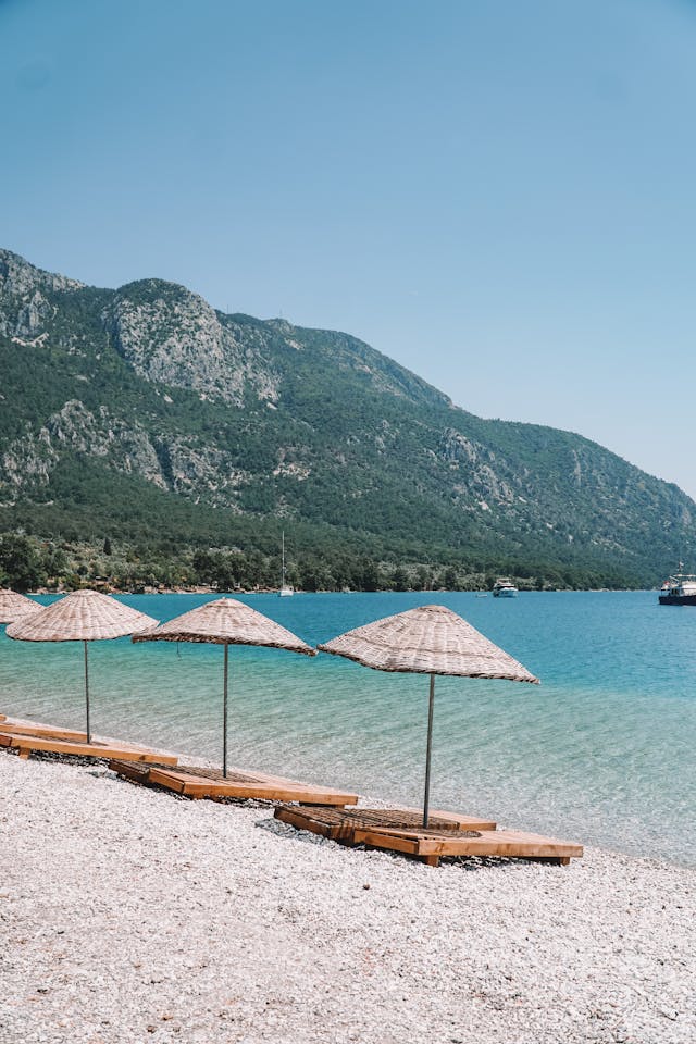 
Sonnenschirme aus Weidengeflecht mit hölzernen Liegestühlen am Meer in Marmaris, Türkei

