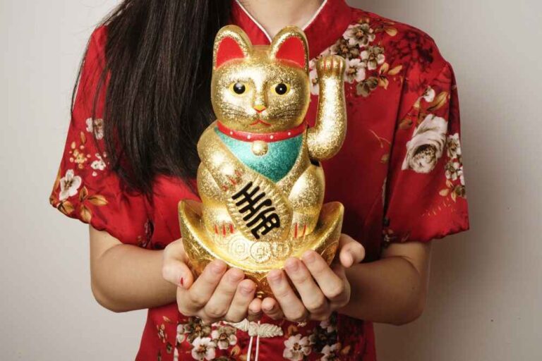 Eine chinesische Glückskatze in den Händen einer jungen Frau in einem traditionellen Kleid