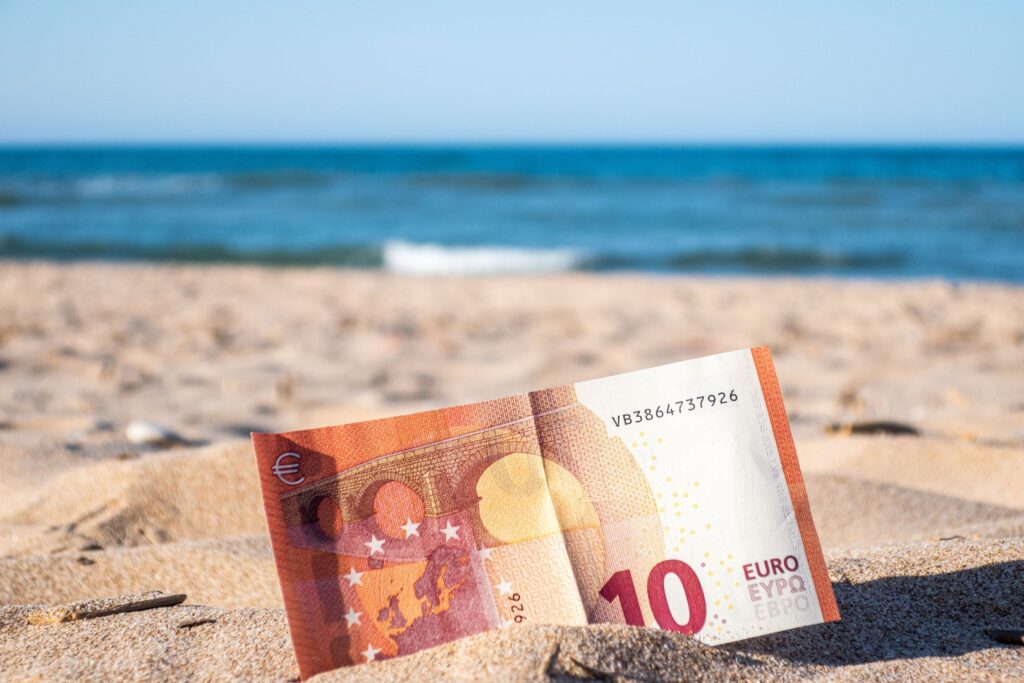 10-Euroschein der im Sand am Strand liegt.