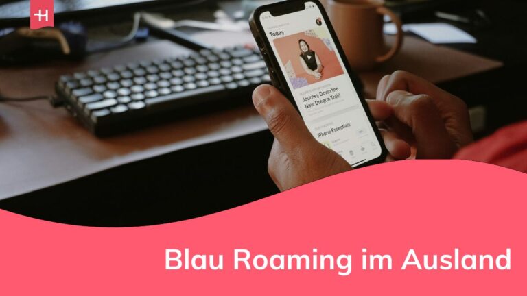 eine Person, die vor einem Computer ein Mobiltelefon benutzt