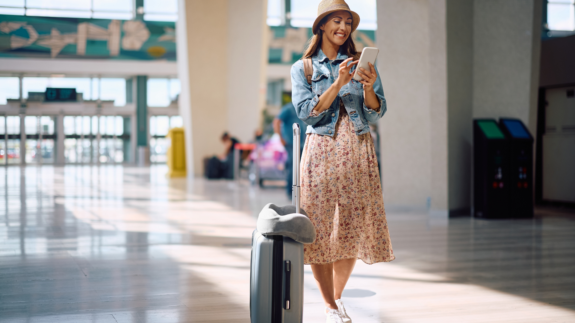 Eine Frau am Flughafen, die auf ihr Handy schaut.