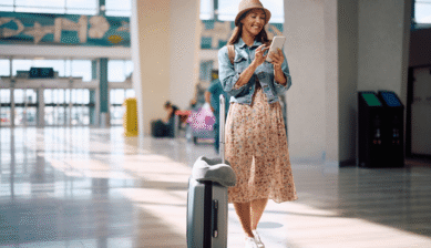 Eine Frau die am Flughafen auf ihr Handy blickt