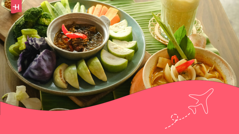 Thailändisches Essen und ein Getränk auf einem festlich gedecktem Tisch.