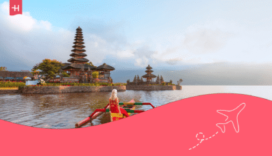 Eine blonde Frau die auf einen Tempel in Bali blickt