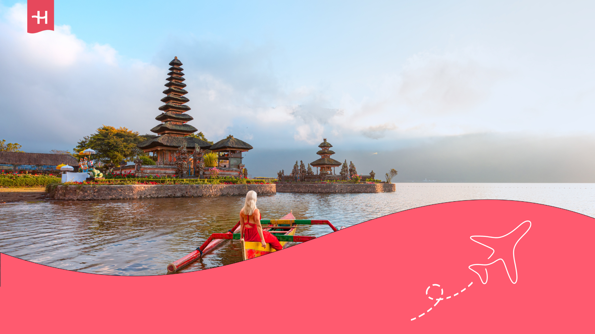 Eine blonde Frau die auf einen Tempel in Bali blickt.