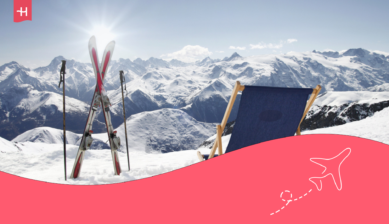 Ein Bergpanorama, eine Sonnenliege und ein Paar Ski, die im Schnee stecken.