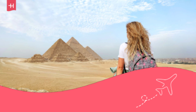 Eine sitzende Frau die auf die Pyramiden von Gizeh blickt.