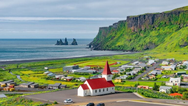 Island im August mit Küstenklippen, kleinem Dorf und grünem Panorama am Meer