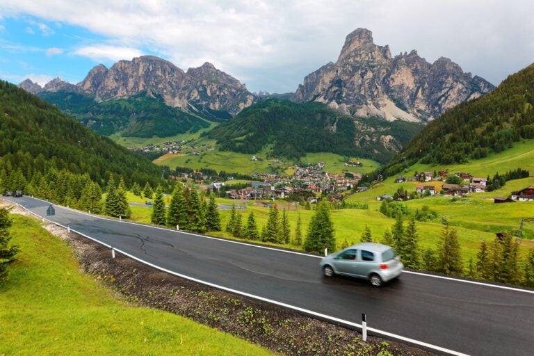Sommerlandschaft mit Dörfern, die über die grünen, grasbewachsenen Hänge der schroffen Berge in Corvara Badia, Trentino, Südtirol, Italien, verstreut liegen.