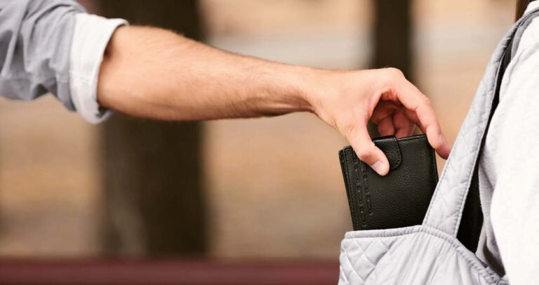 Ein Mann stiehlt eine Brieftasche aus der Handtasche einer Frau.