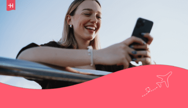 Eine junge Frau blickt mit einem breiten Lächeln auf ihr Handy – Titelbild für einen Artikel über die Nutzung von Tinder ohne Telefonnummer.