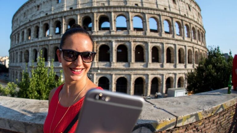 Frau macht ein Selfie vor dem Kolosseum in Rom