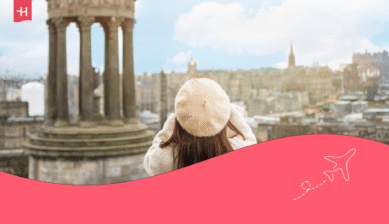 Eine Touristin mit Birett-Mütze blickt vom Calton Hill auf Edinburgh. Passend zum Thema: 10 Fakten über Schottland.