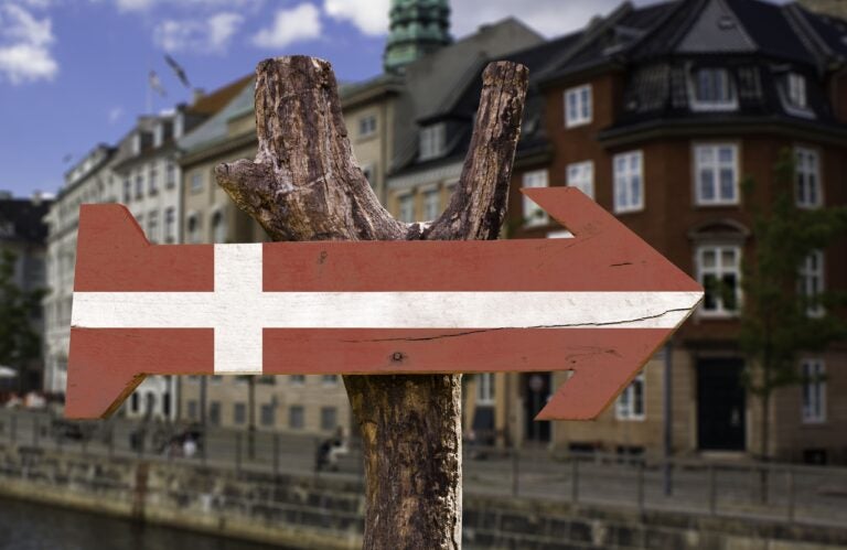 Hölzerner Wegweiser, bemalt in den Farben der dänischen Flagge.