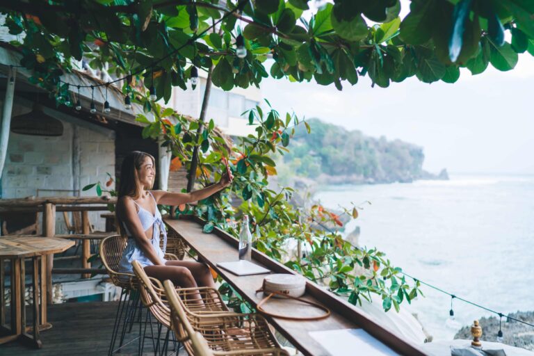 Frau macht ein Selfie in einem Café mit Meerblick in Bali. 
