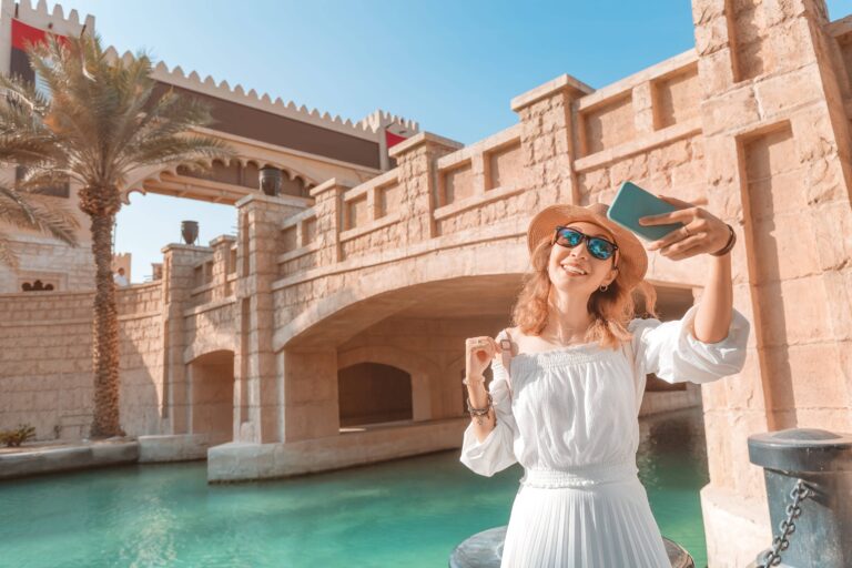 Touristin macht ein Selfie vor den traditionellen Brücken und Wasserwegen des Madinat Jumeirah in Dubai.