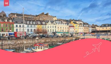 Bunte Häuserreihe am Hafen von Cobh; die Grafik illustriert Fakten über Irland.