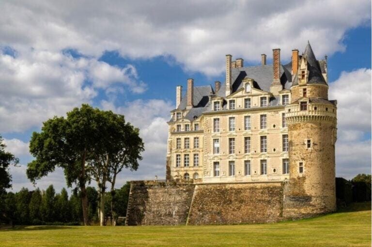 Ein imposantes historisches Schloss aus hellem Stein mit runden Türmen
