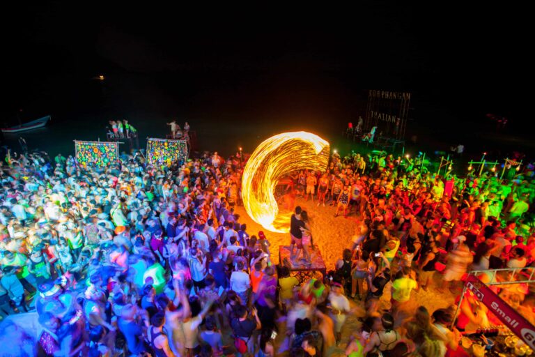 Menschenmenge am Strand beobachtet einen brennenden Feuerkreis während der Full Moon Party. 
