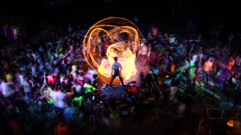 Feuertänzer inmitten einer feiernden Menschenmenge bei der Full Moon Party in Thailand.