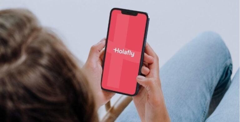 Eine Person hält ein Smartphone mit der geöffneten Holafly-App in den Händen.