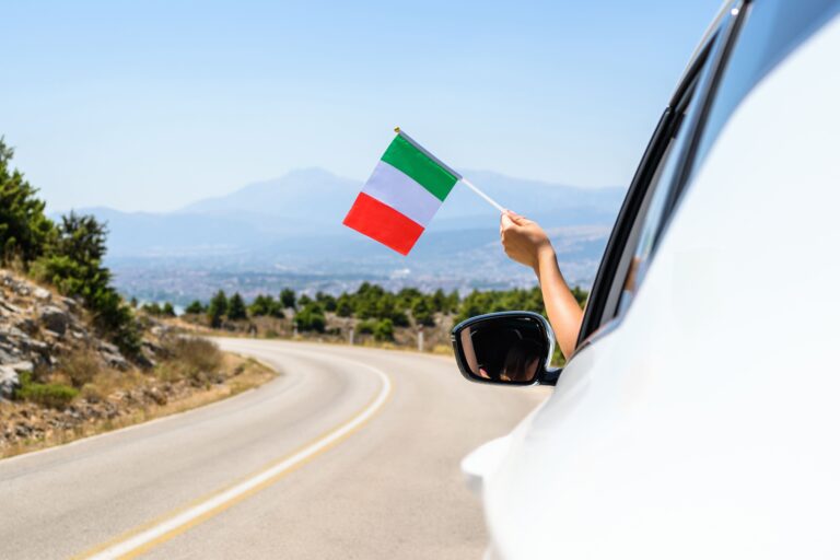 Eine Hand hält eine kleine italienische Flagge aus dem Fenster 