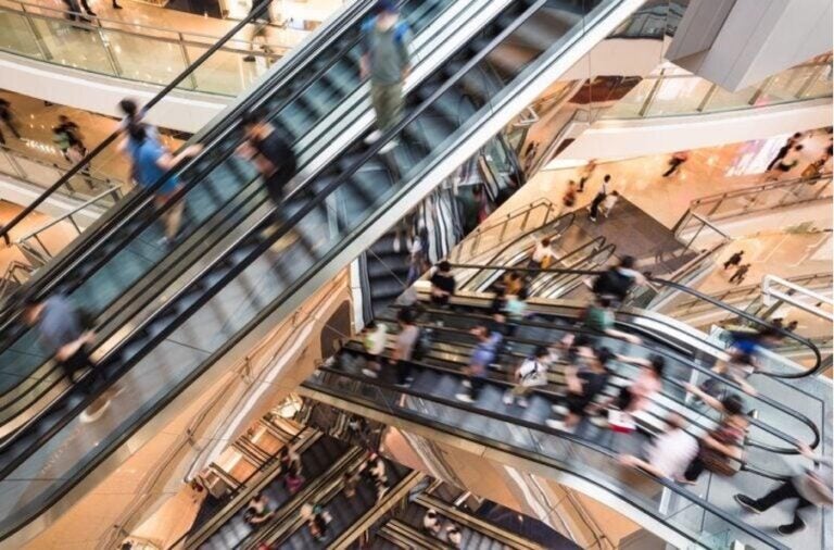 Eine belebte Szene mit vielen Rolltreppen und Menschen im Kaufhaus Le Bon Marché