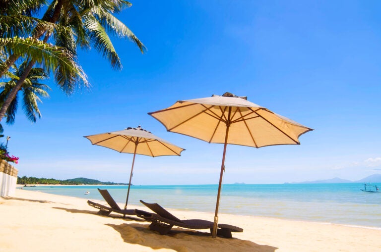 Zwei Sonnenschirme und Strandliegen im Sand des Maenam Beach auf Koh Samui,