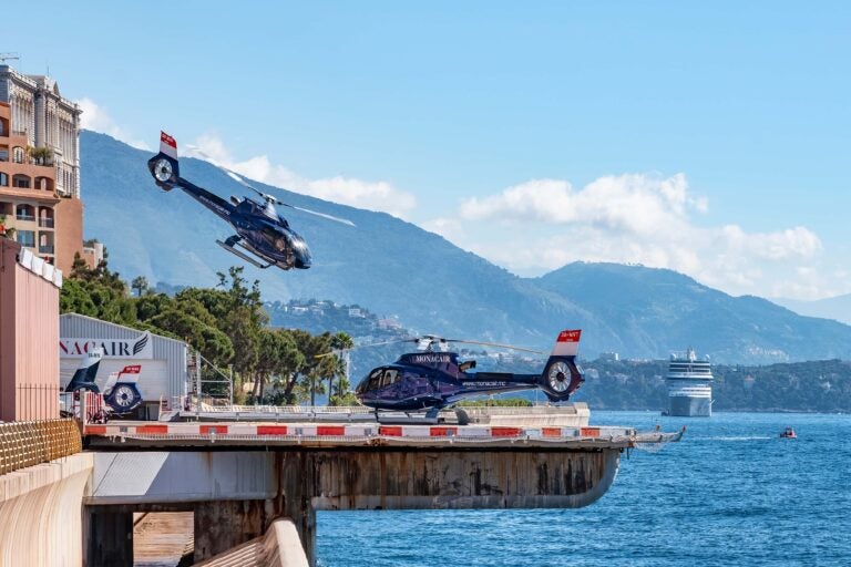 Zwei dunkelblaue Monacair-Hubschrauber am Heliport von Monaco direkt am Meer.