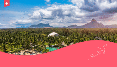 Tropische Hotelanlage auf Mauritius mit Palmen, einem Pool und Bergen im Hintergrund.