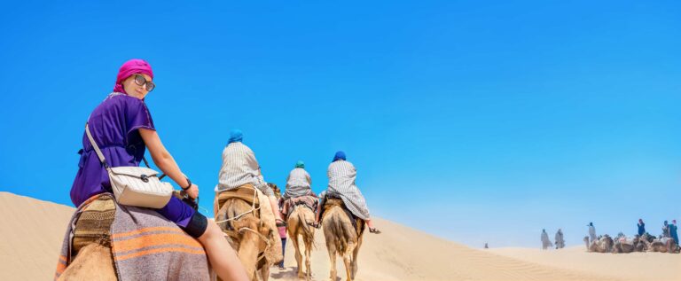 Touristin auf einem Kamel in der Wüste.